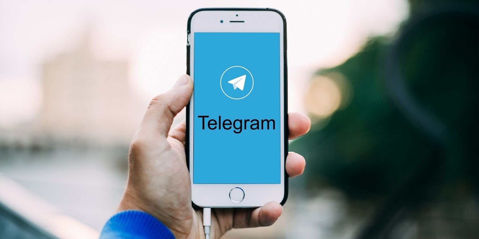 The Telegram app opening on an iPhone being held by somebody.