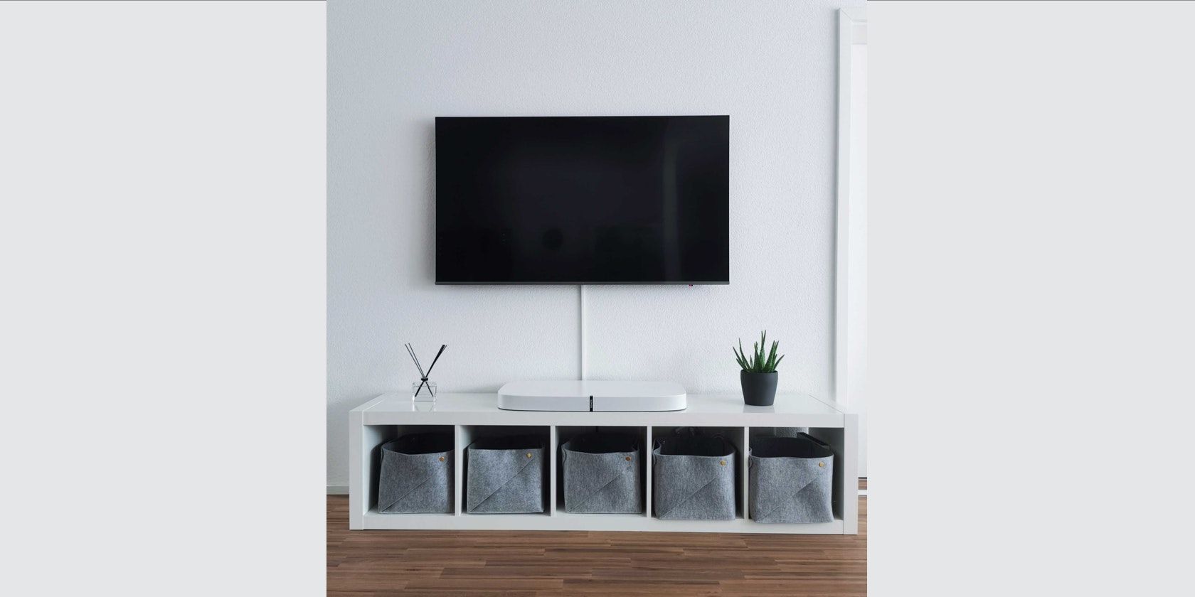 A photo of a television mounted on the wall with the cables running through cable trunking below it.