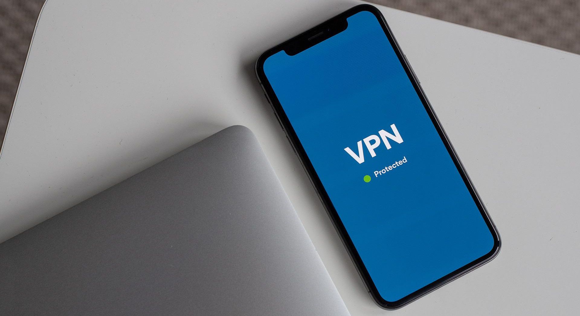 برنامه vpn روی صفحه گوشی هوشمند در کنار لپ تاپ