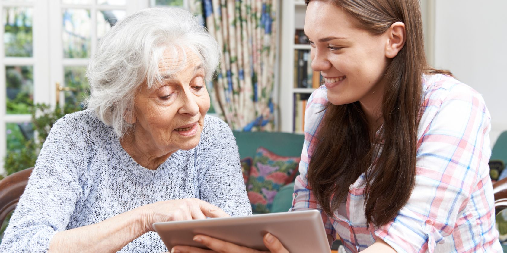 young woman showing older woman a tablet