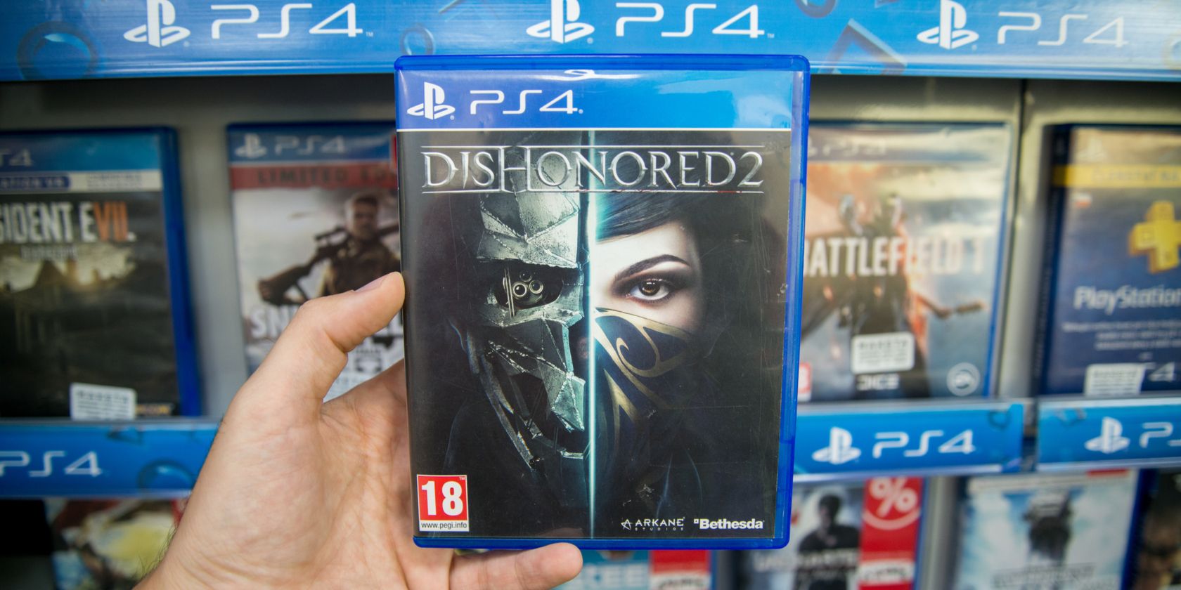 Hand holding Dishonored 2 PS4 game case in a store