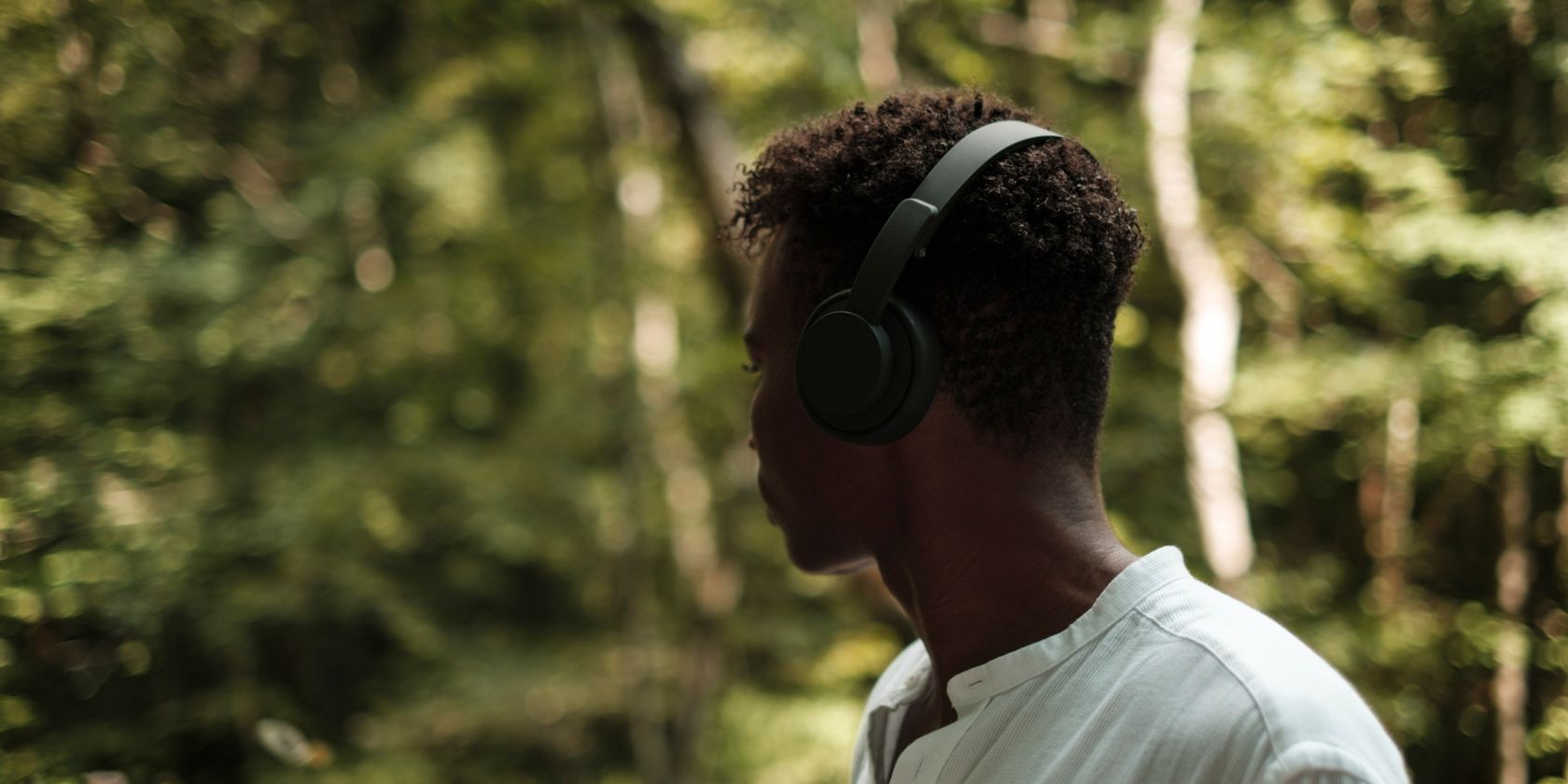 Screenshot showing a man looking into a forest wearing headphones