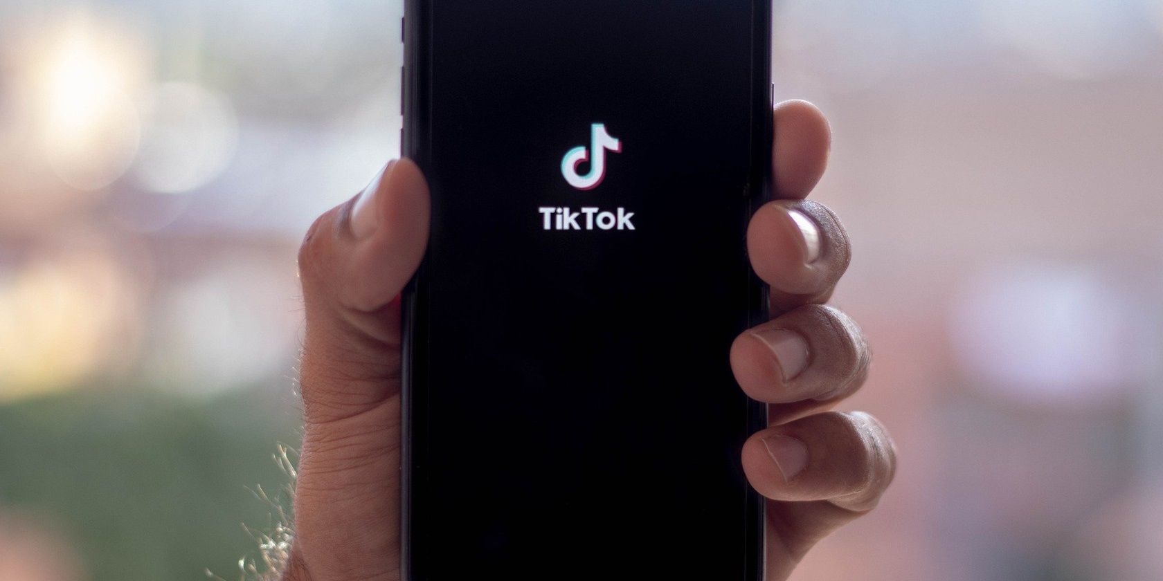Main tenant un smartphone avec TikTok écrit dessus.