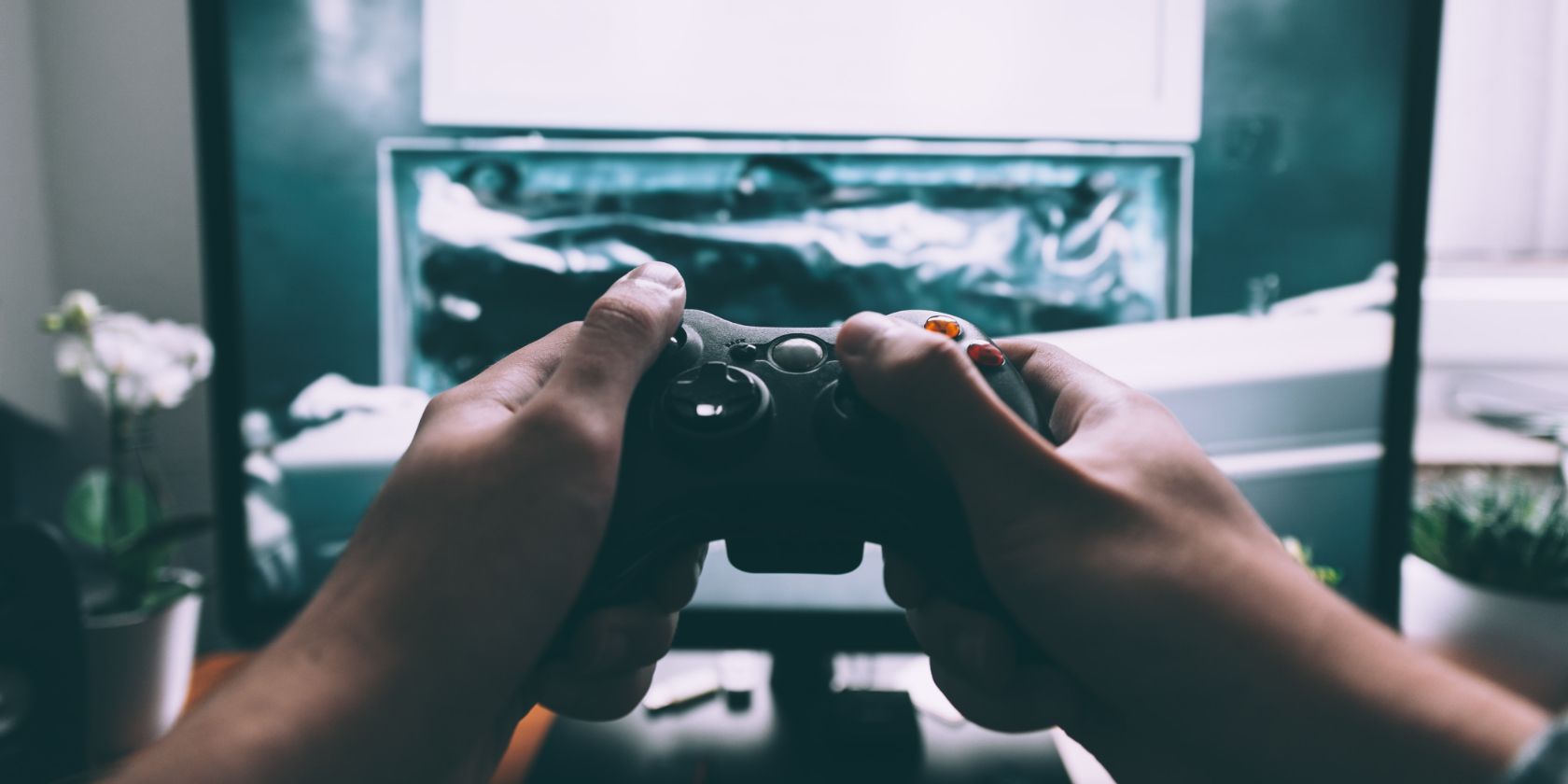 Hands holding a video game controller in front of TV