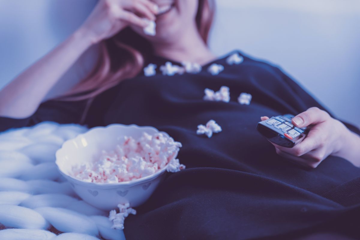 Wanita makan popcorn dan menonton tv
