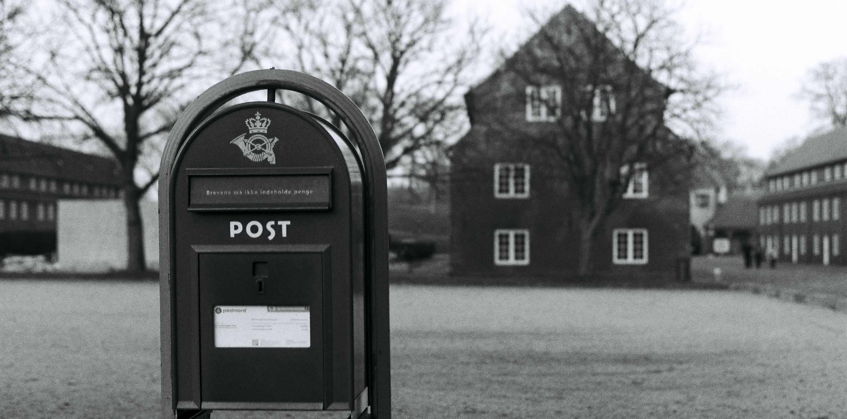 black and white photo of mailbox in front of house