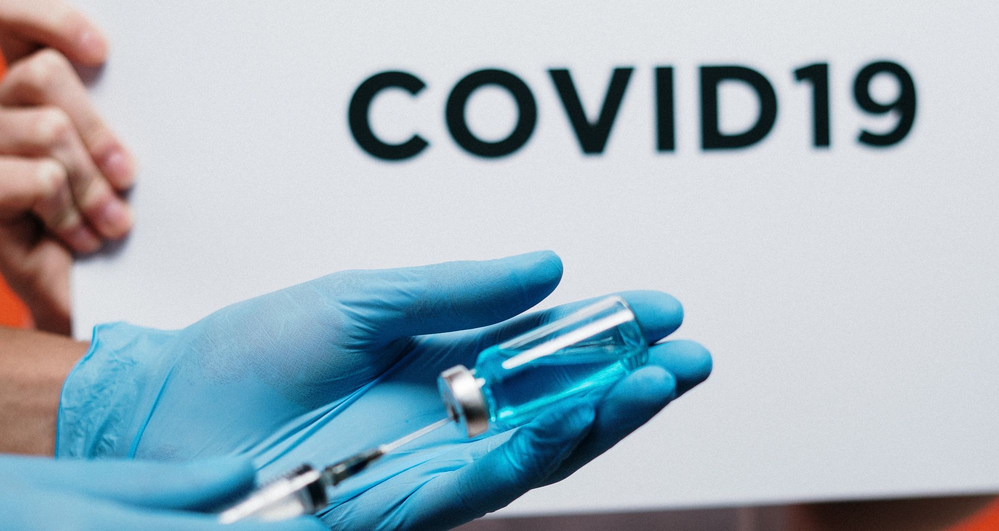 person in gloves holding covid 19 vaccine in syringe 