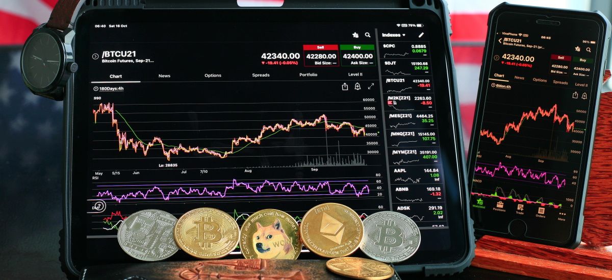 A picture showing crypto coins and technical charts on smart devices