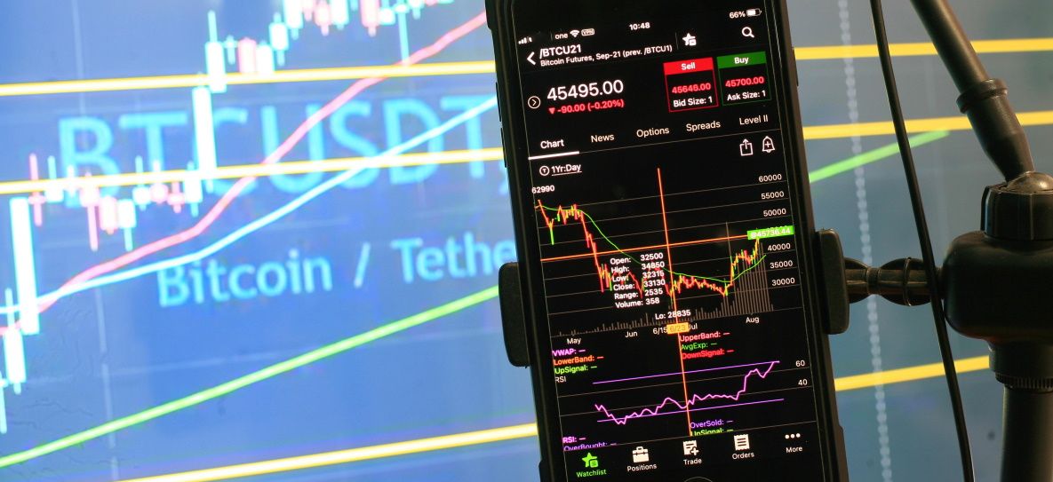 a phone showing a BTCUSD chart while being hanged on a stand 