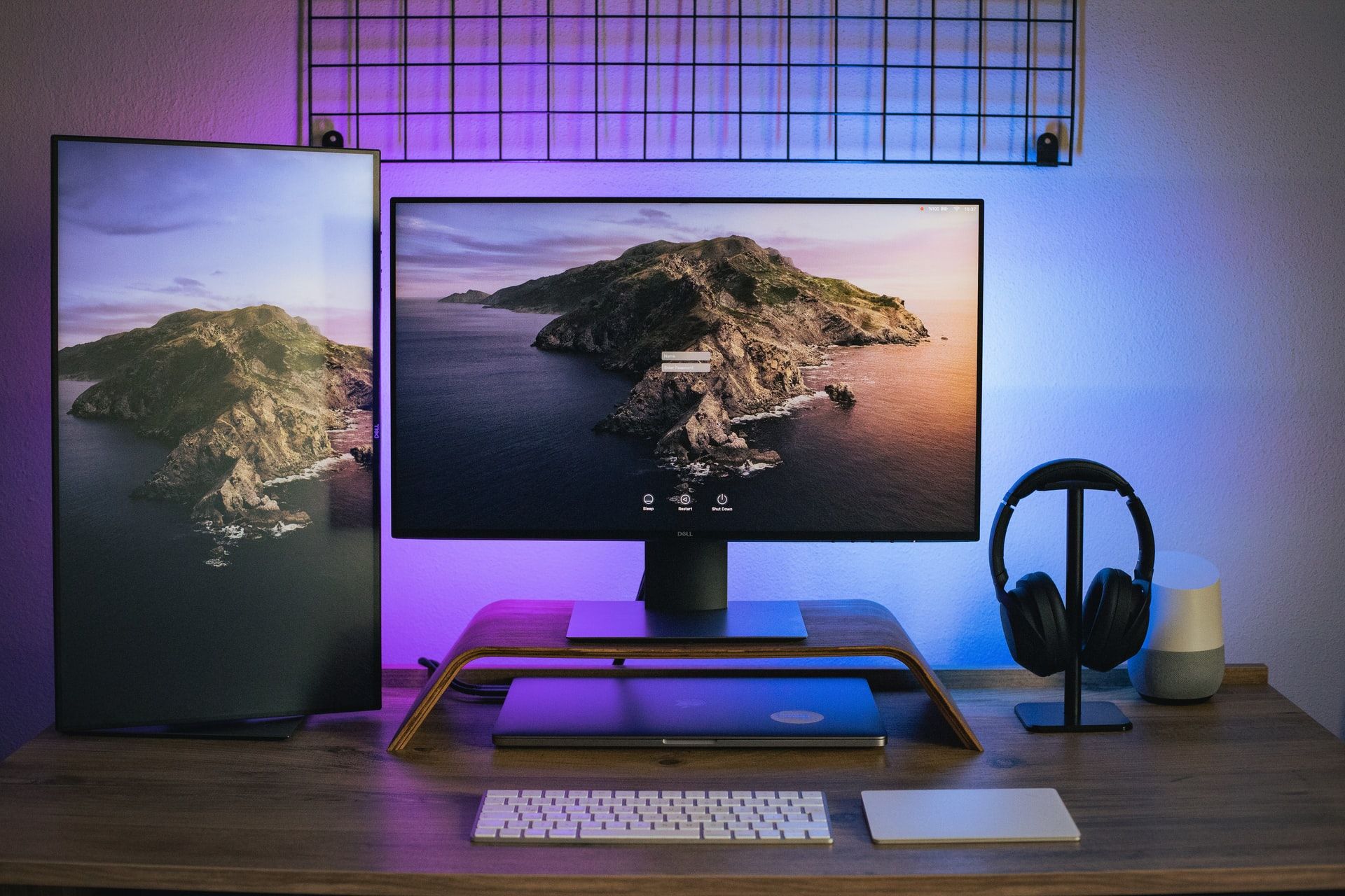 A photo of a multiple screen computer desktop setup backlit with purple/blue LED lights