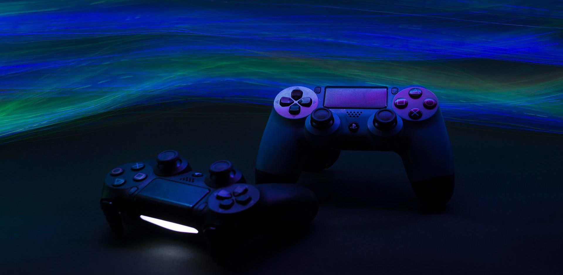 pair of playstation controllers under dark lighting