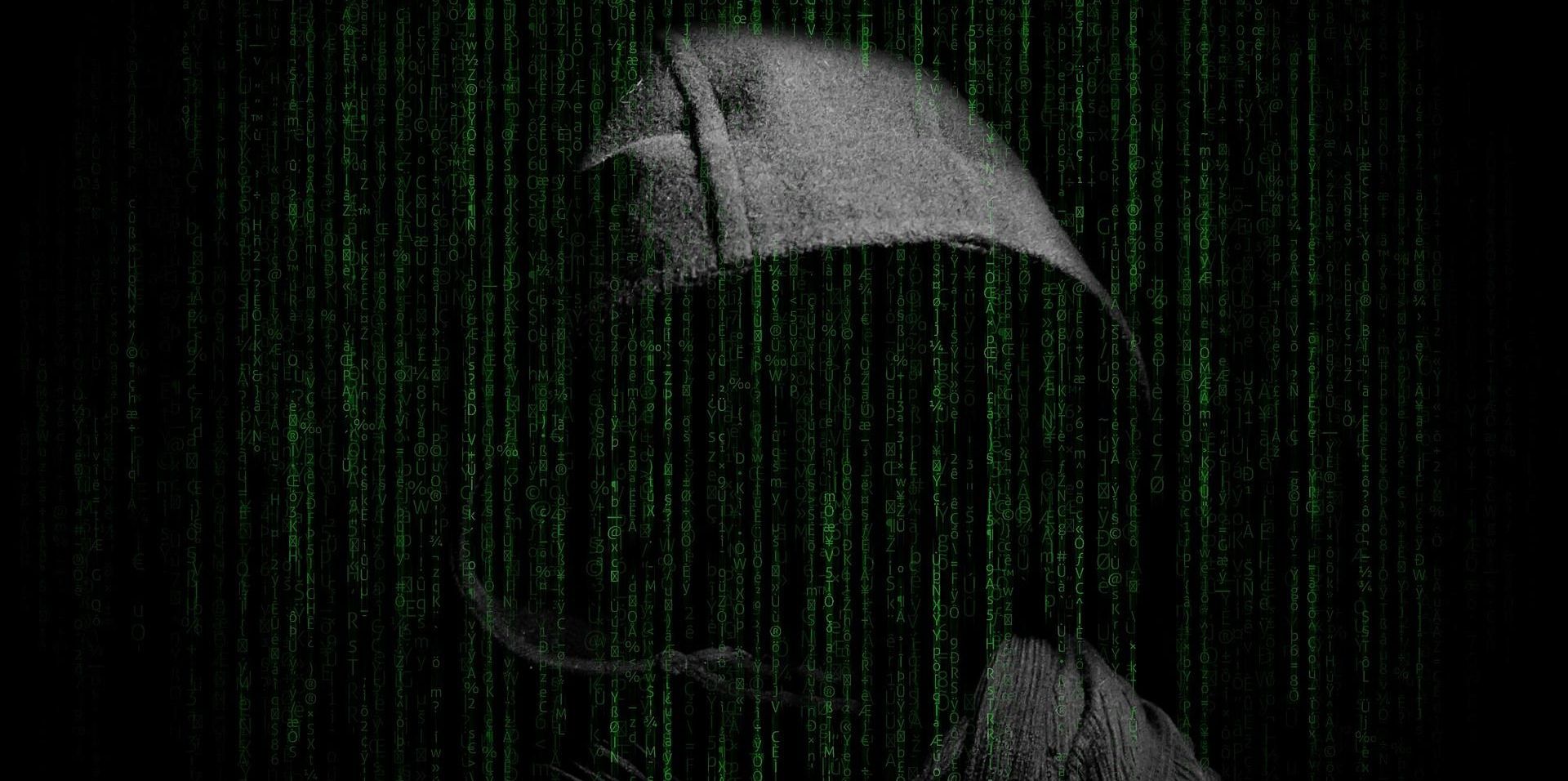 hooded man behind green computer code