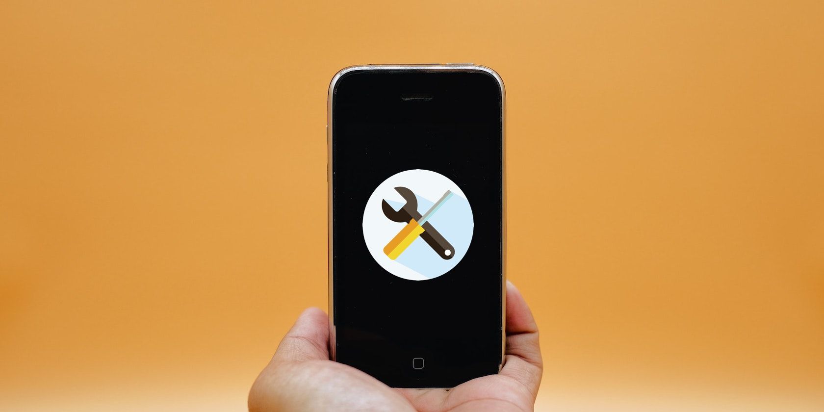A photo of a hand holding up an iPhone with a repair tool symbol on the screen