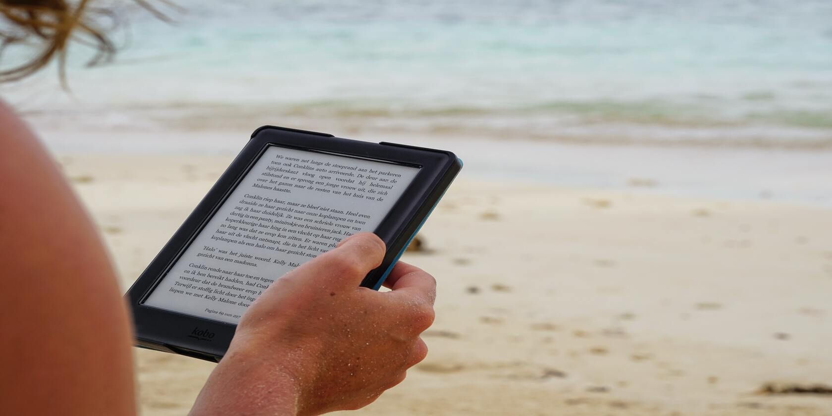 Person holding Kindle on beach