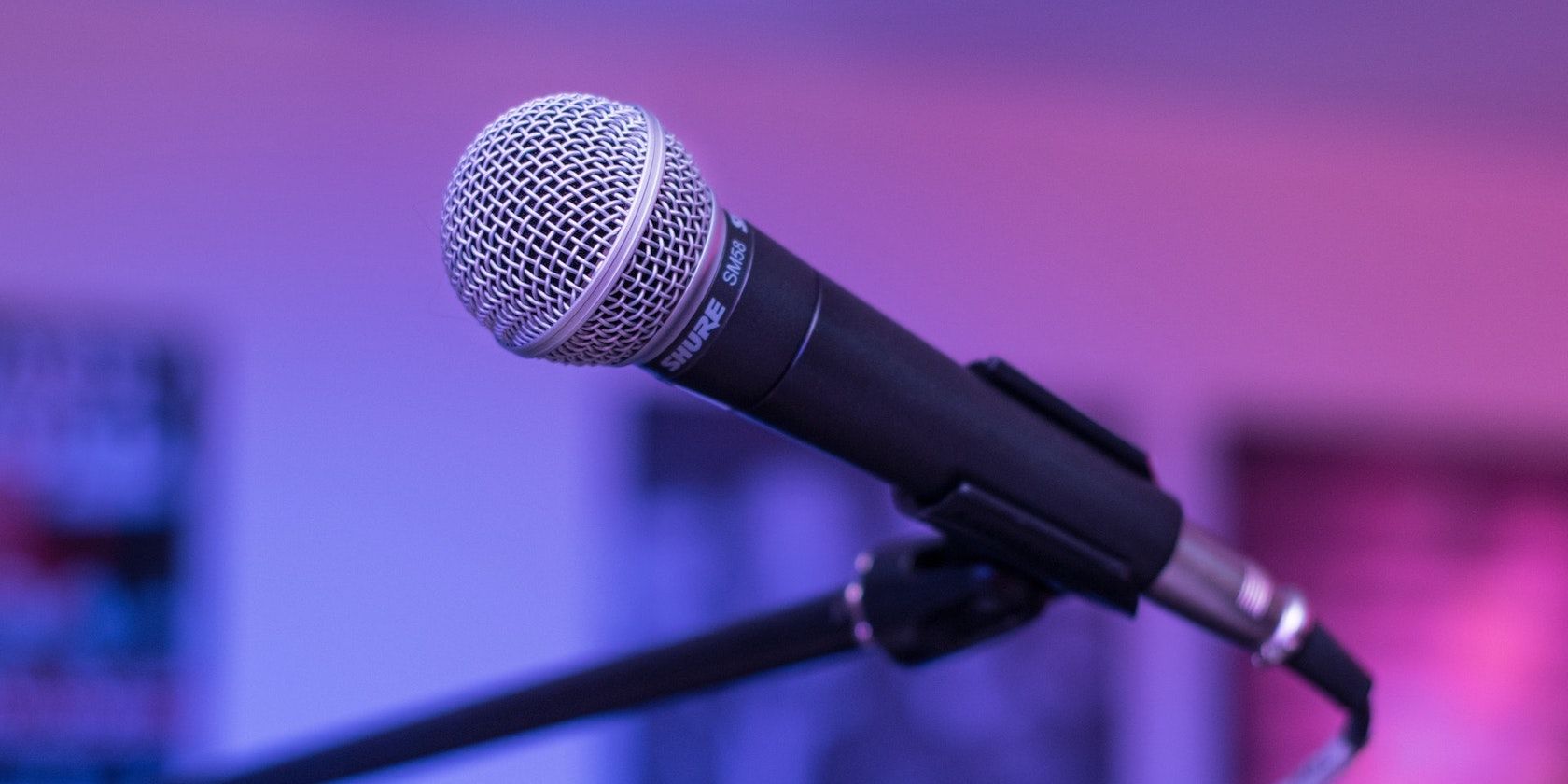 A close up photo of a SM58 vocal microphone against a purple and blue background