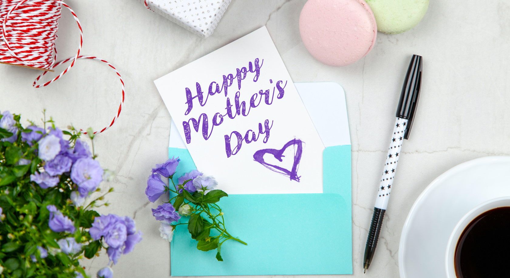Mother's Day card on table with pen and macarons and flowers