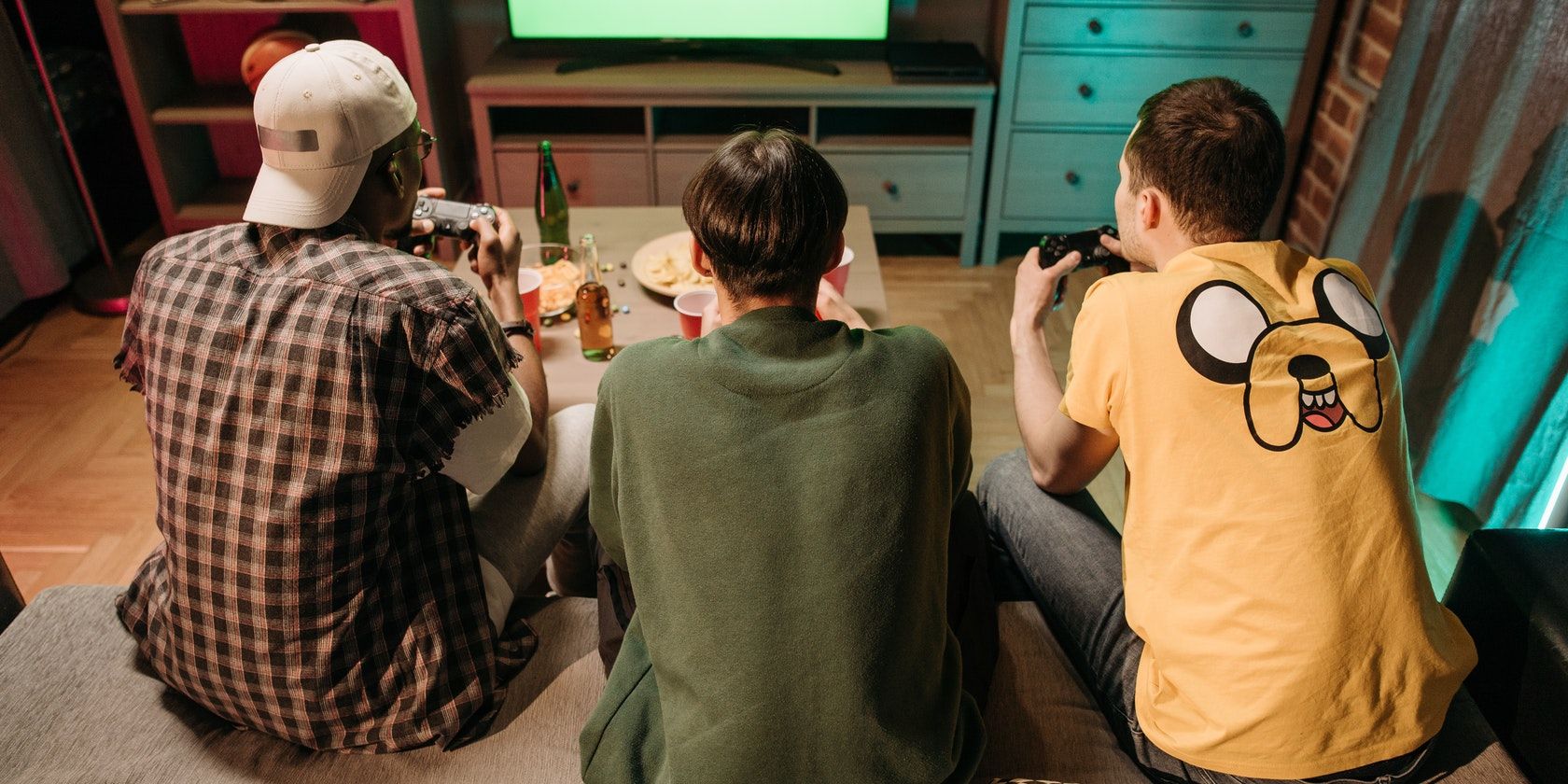 Three men facing a tv playing games