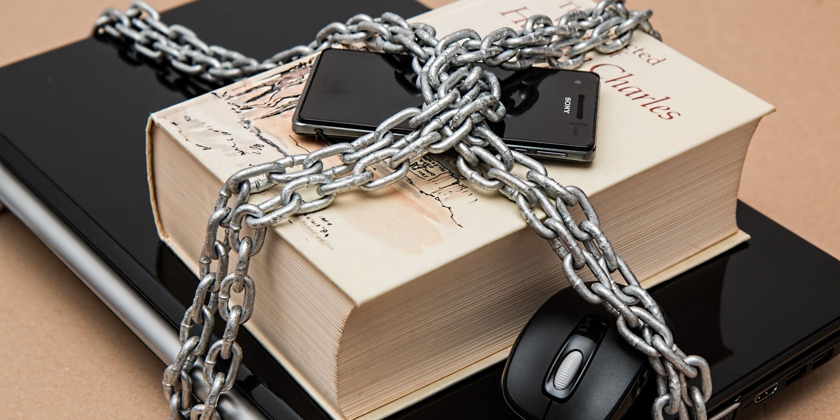 Phone on top of a thick book, both surrounded by a large metal chain