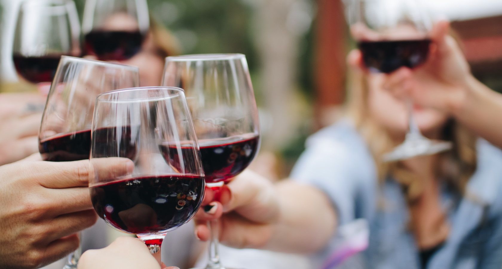 People holding wine glasses with red wine and toasting