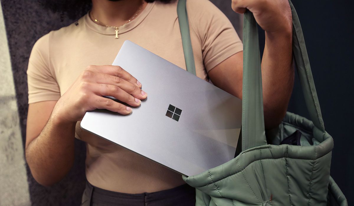 Woman putting a Microsoft Surface into a green bag.