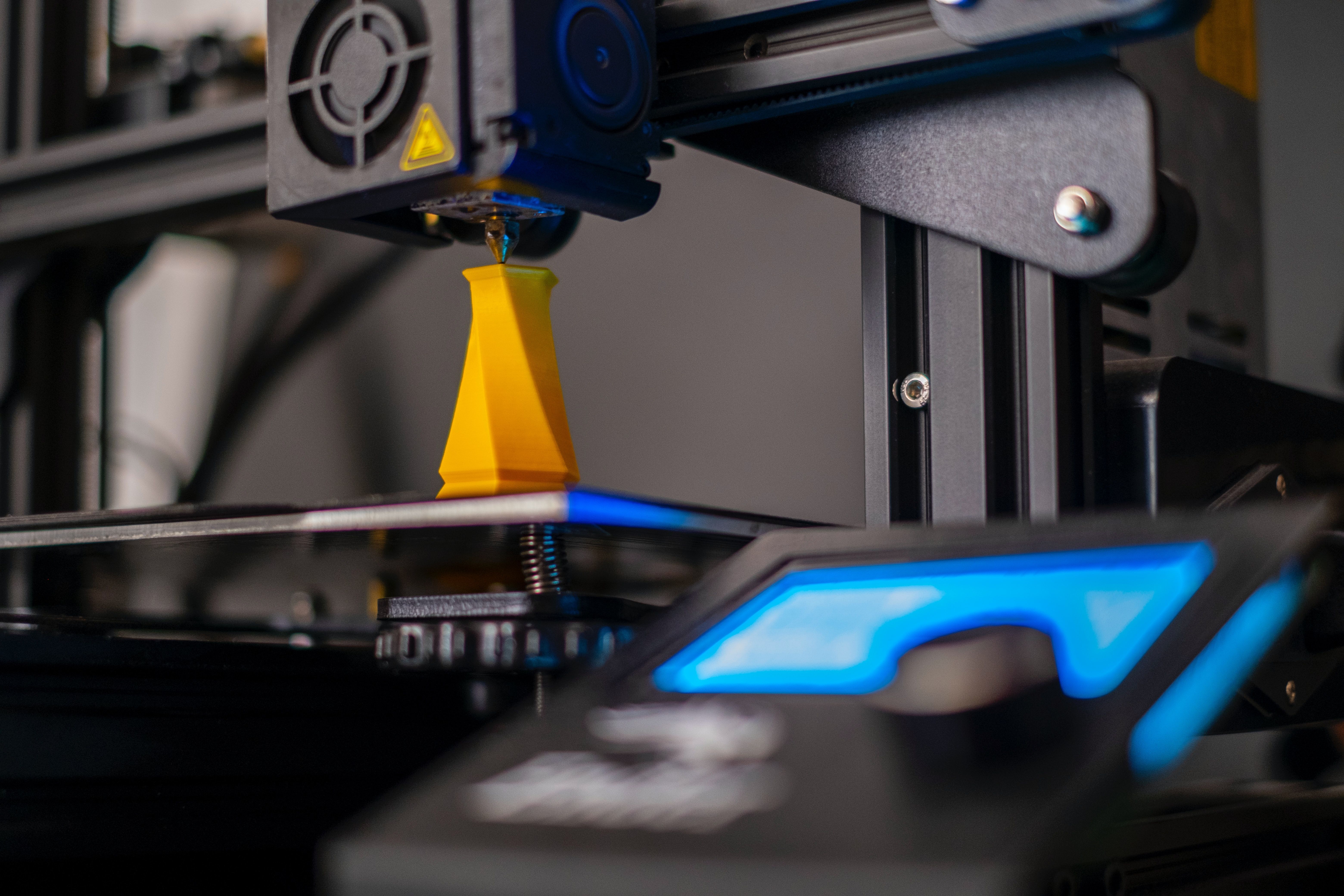 A 3D printer printing a yellow vase