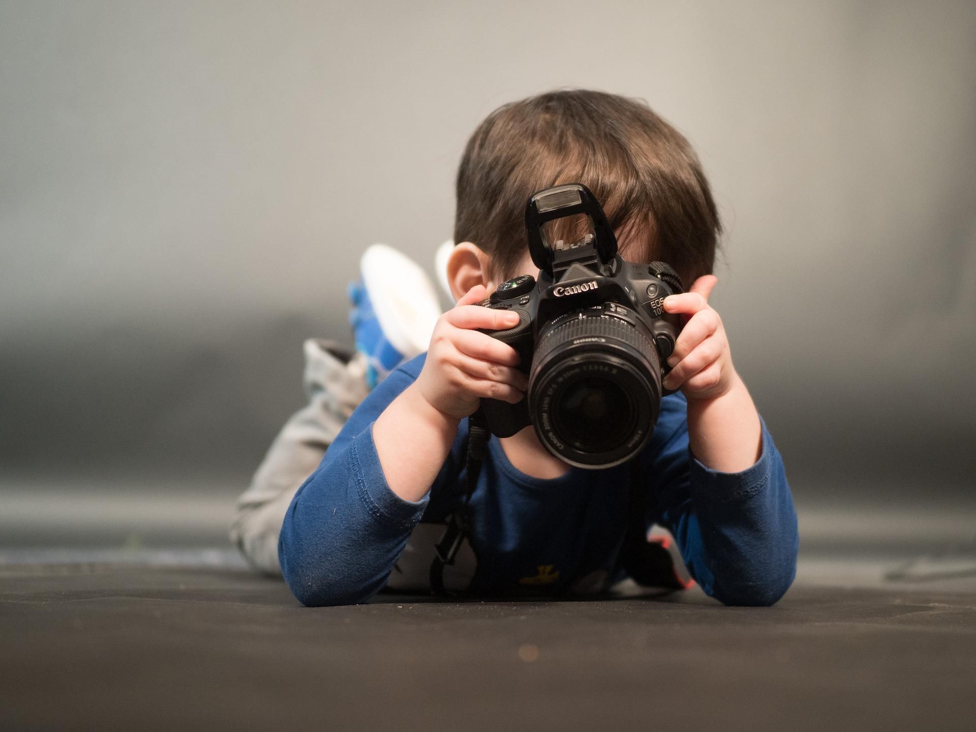 Child lying down with a camera