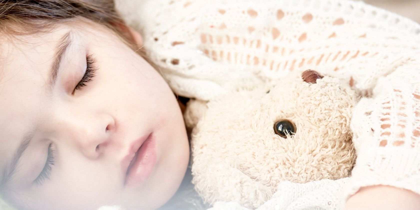 Photo showing a sleeping child holding a teddy bear