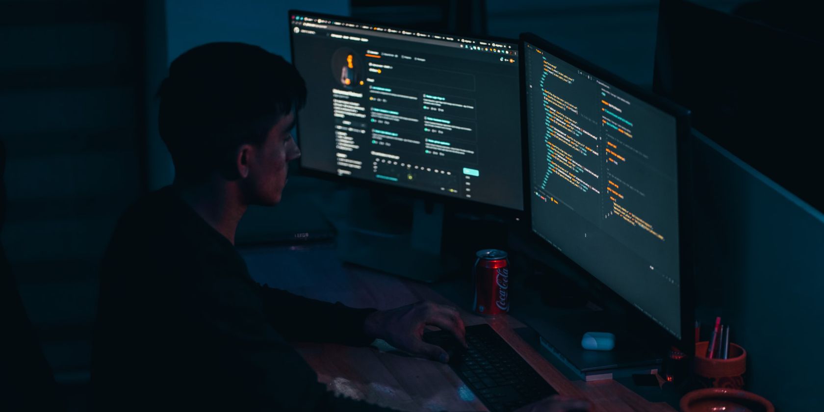 A programmer working on multiple monitors with the screens showing lines of code.