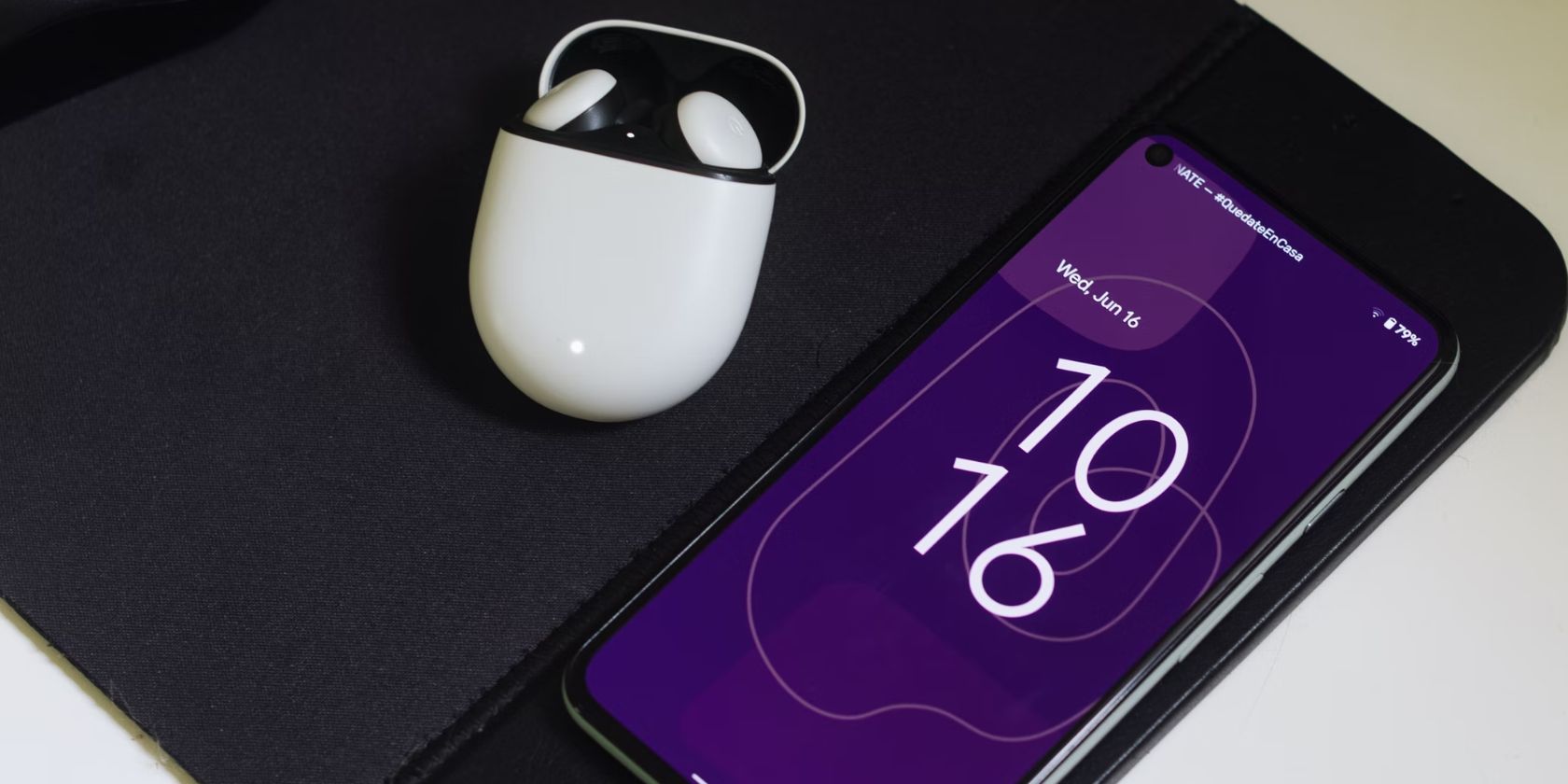 android smartphone with a purple lockscreen next to a pair of earbuds