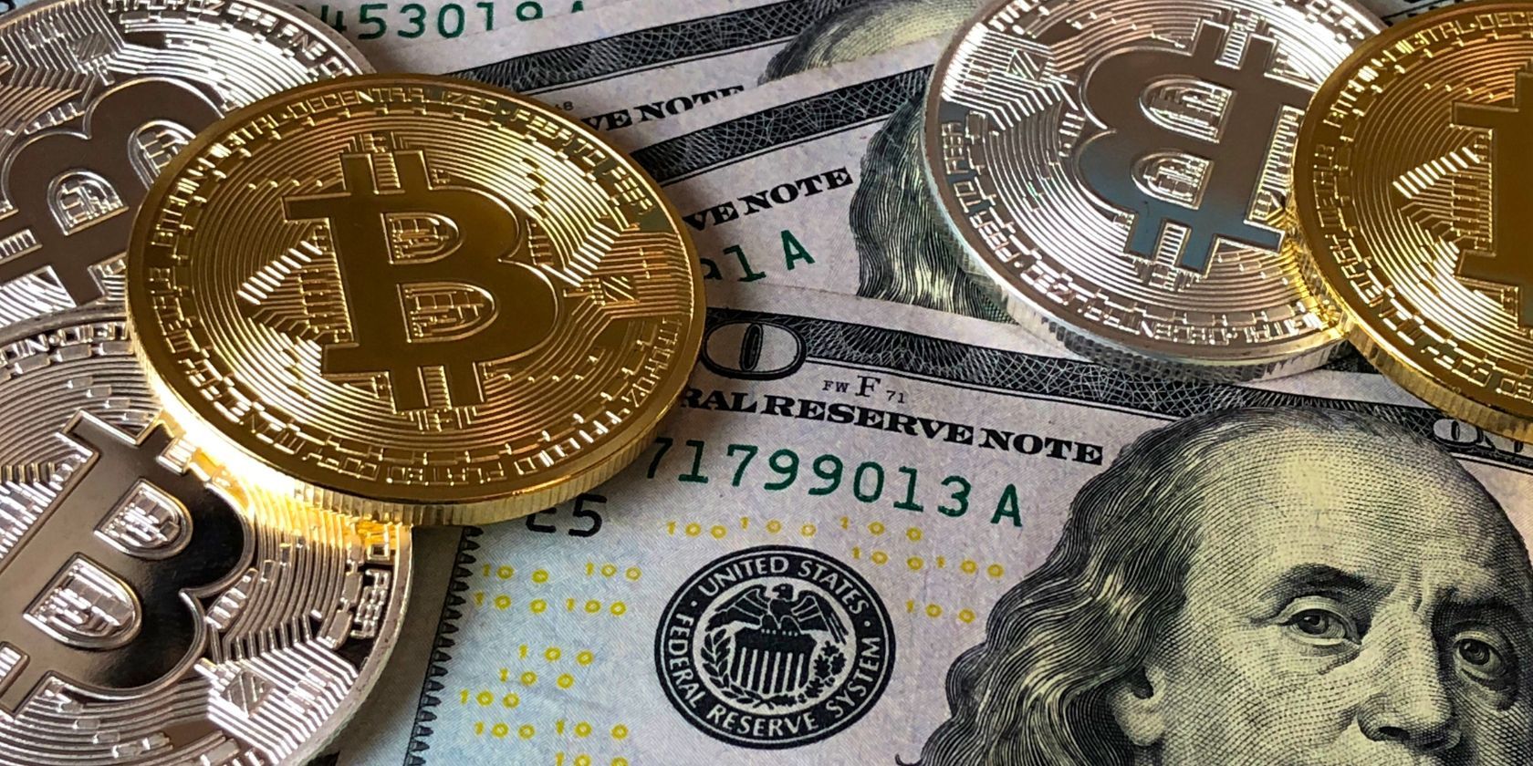 bitcoin coins on top of united states dollar bills