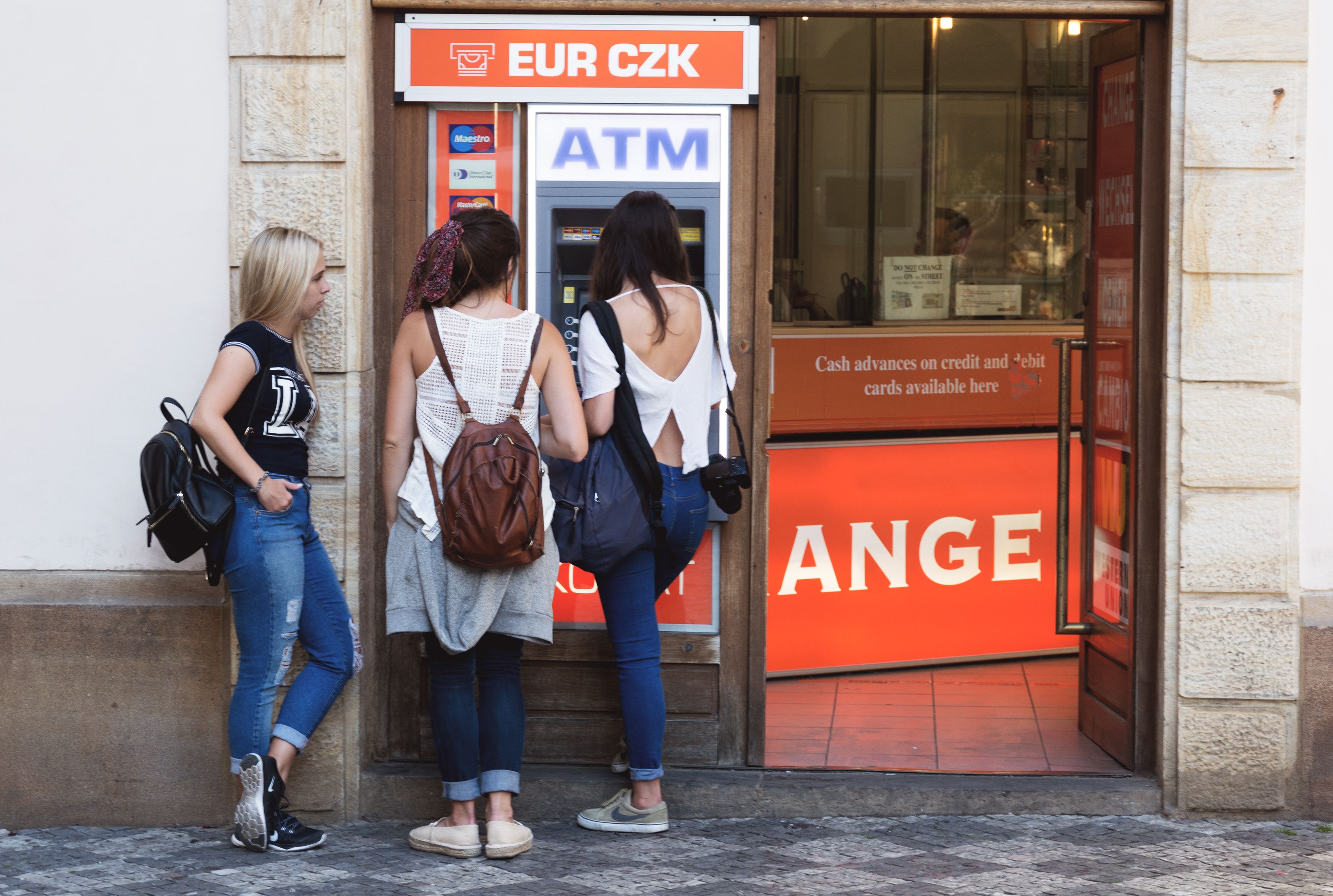 Three young women using an ATM