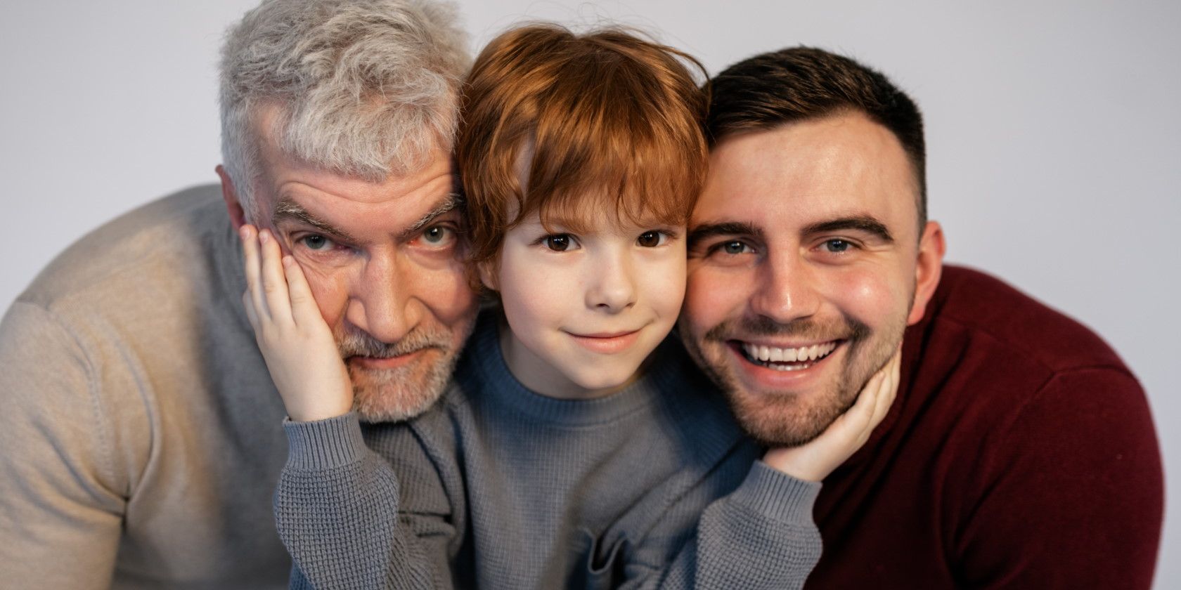 Three members of family young boy man and granddad smiling