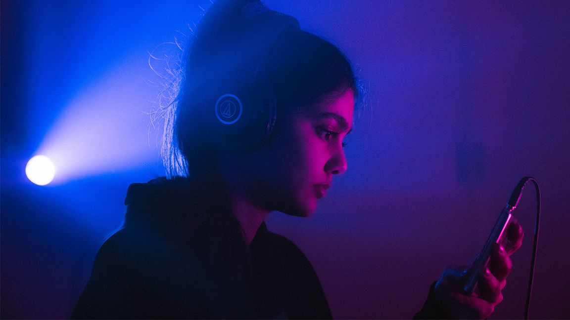 Woman listening to music in dim room.