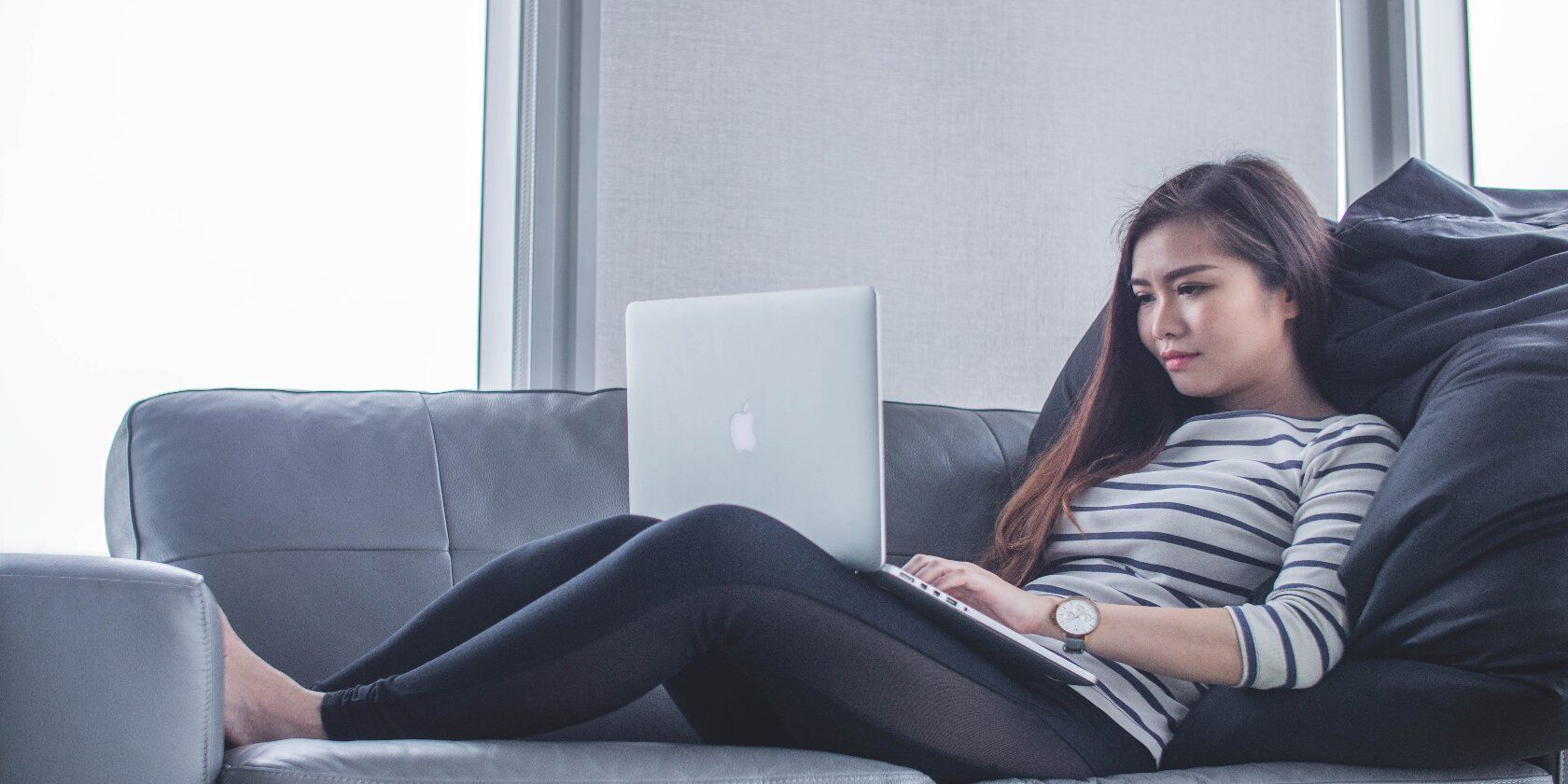 Woman working from home using her laptop on the sofa. 