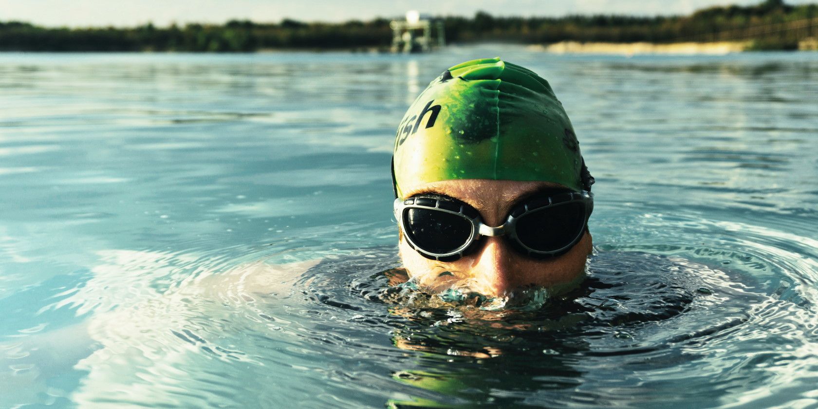 Man swimming in body of water wearing swim goggles