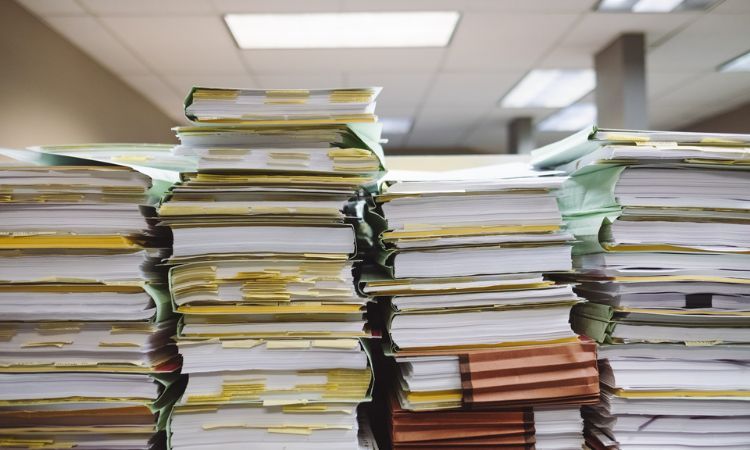 four tall stacks of papers in paper folder and binders in an office