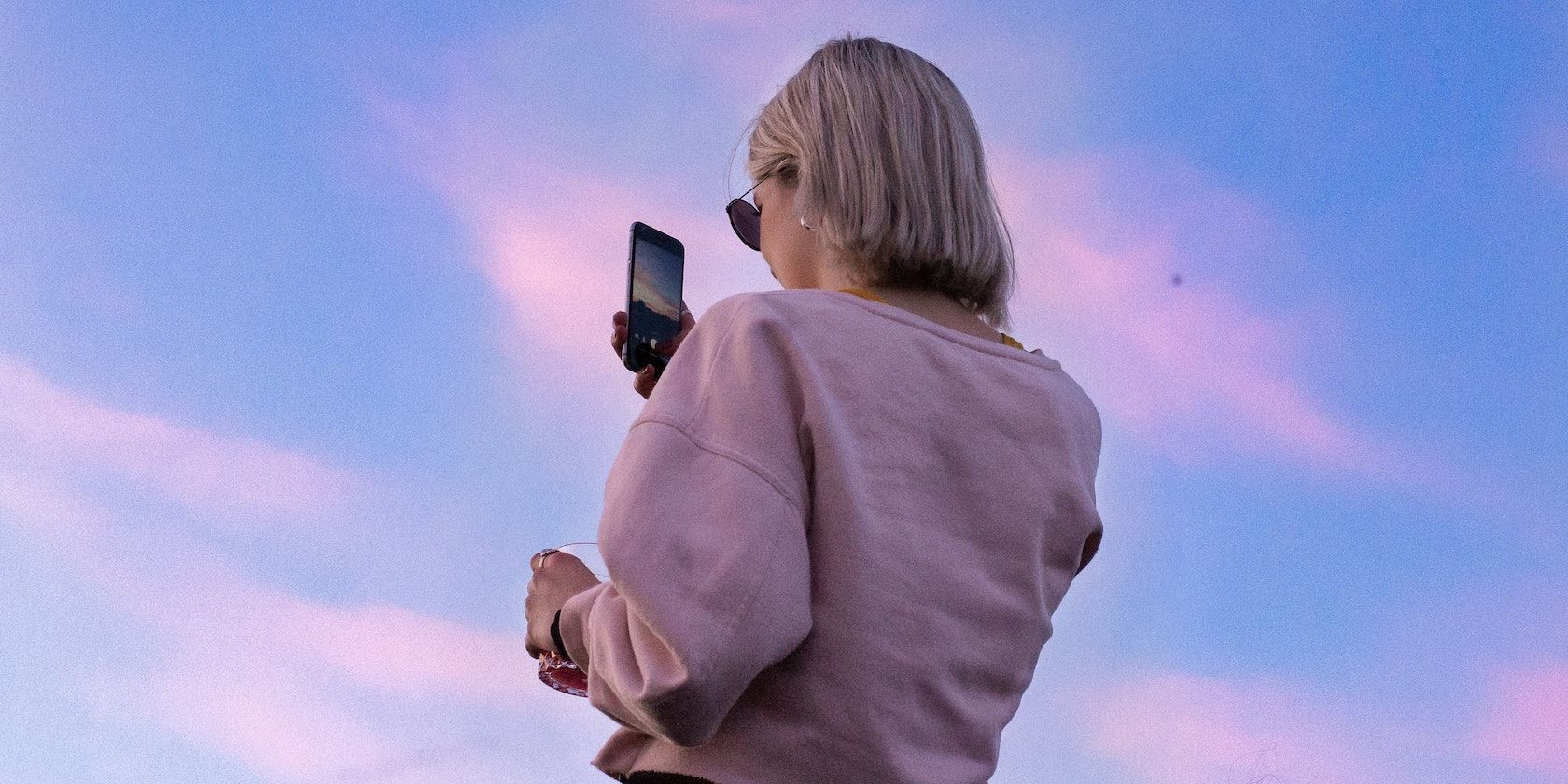 A girl taking a video with her phone of the sky looking pretty 