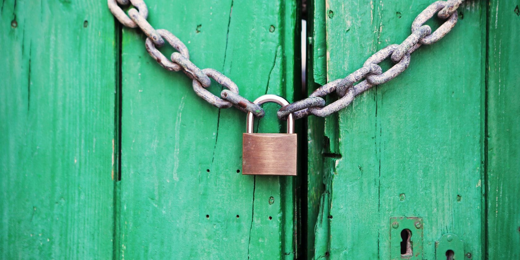 A green wooden door with a chain and padlock