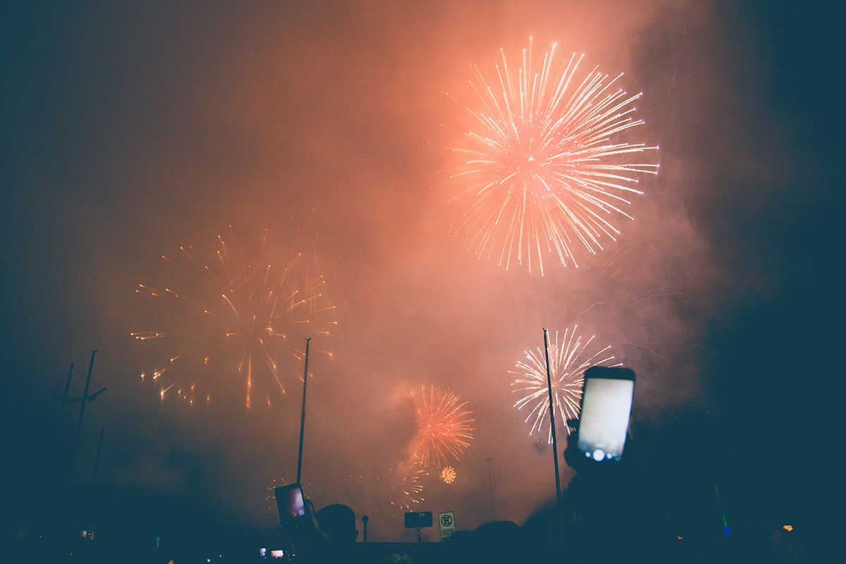 A smartphone taking a photo of fireworks in the fog.
