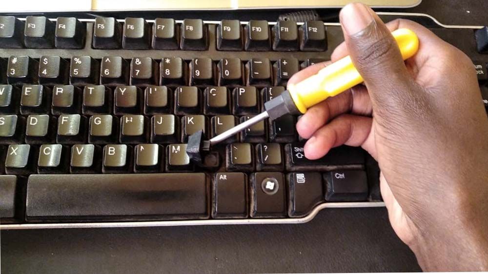 Removing the keycap from the keyboard using a screw driver