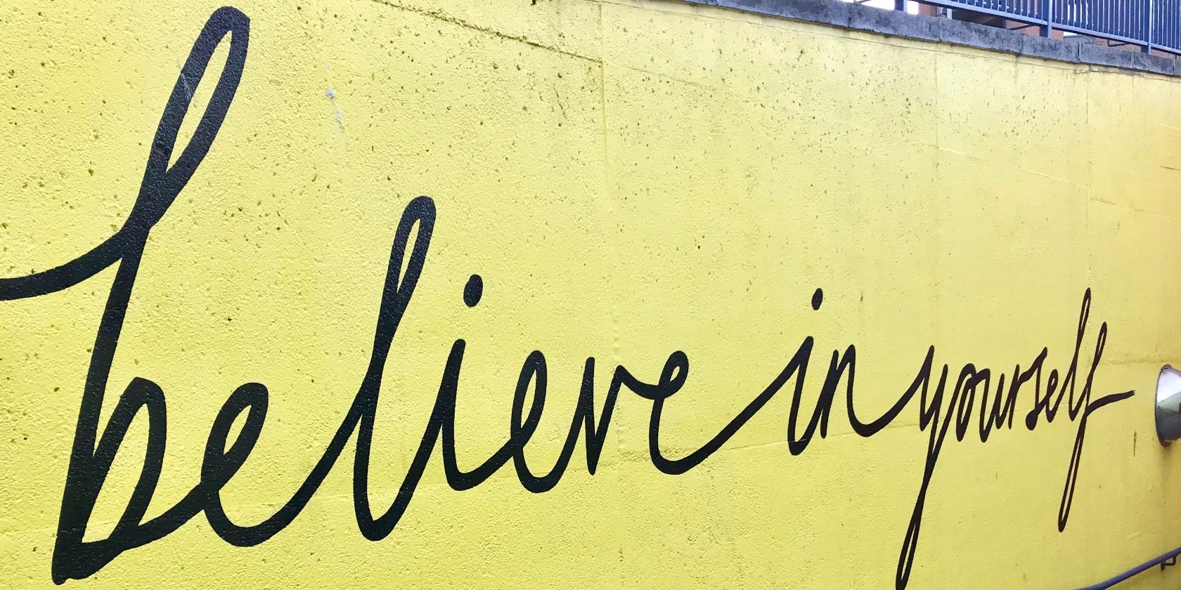 sign on yellow wall that says believe in yourself