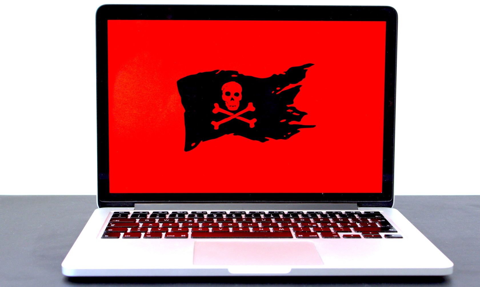 Skull and crossbones pirate flag displayed on red laptop screen