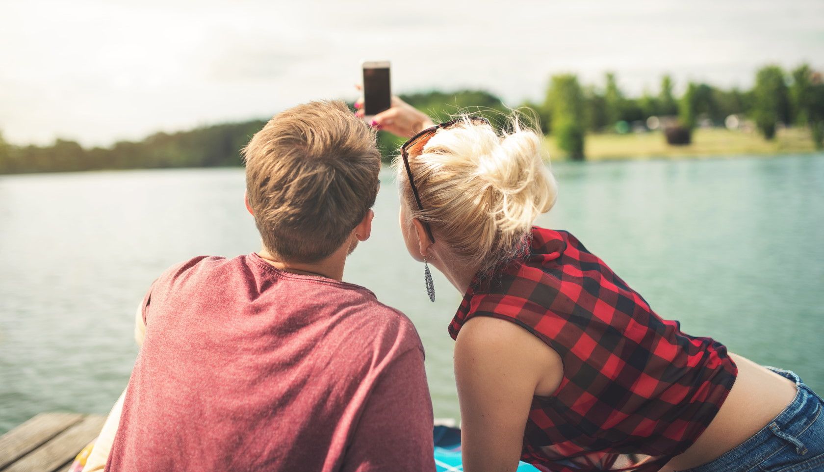 Couple taking selfie pictures next to a lake