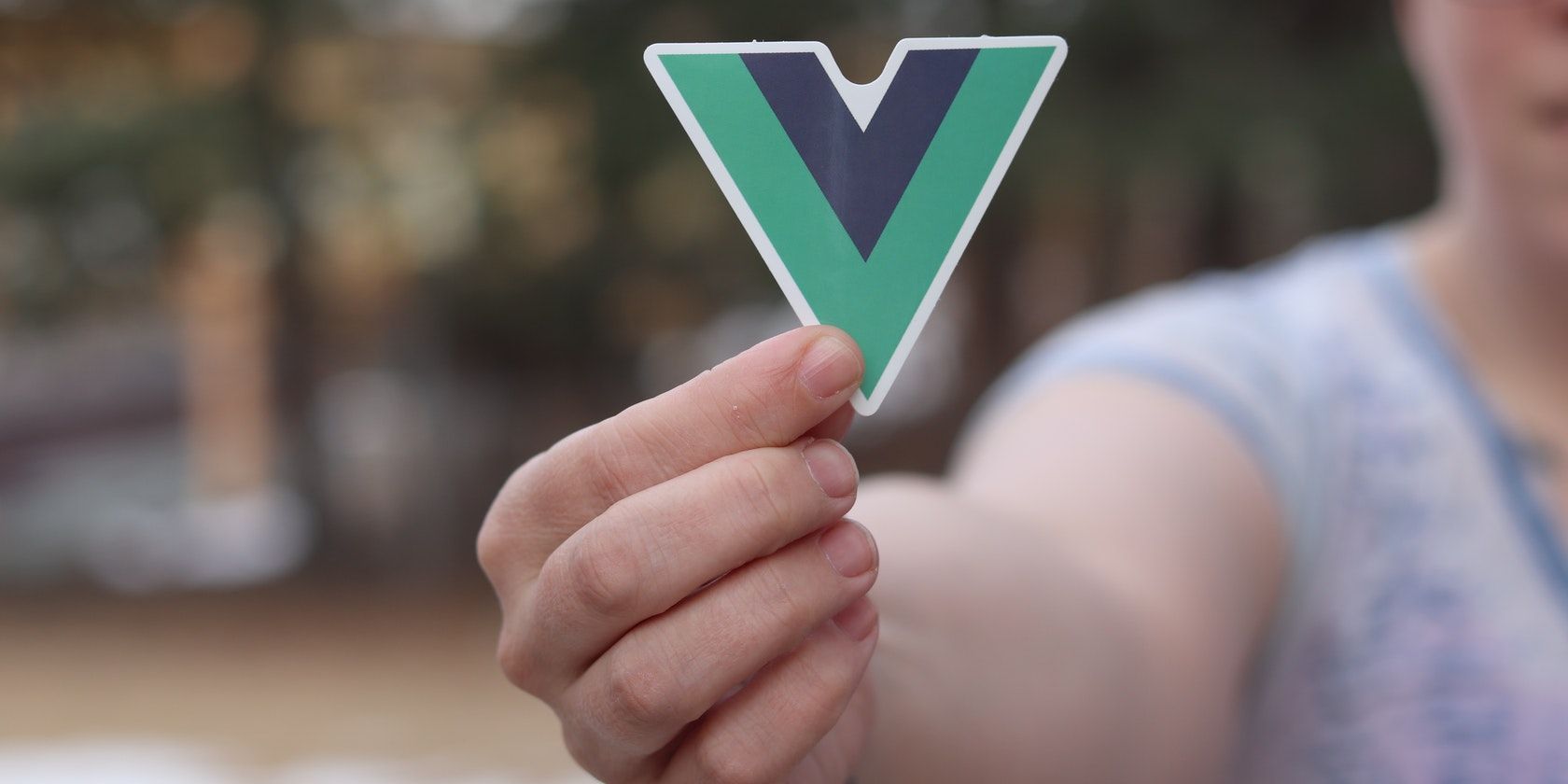 A close-up of a hand holding up a vue.js sticker
