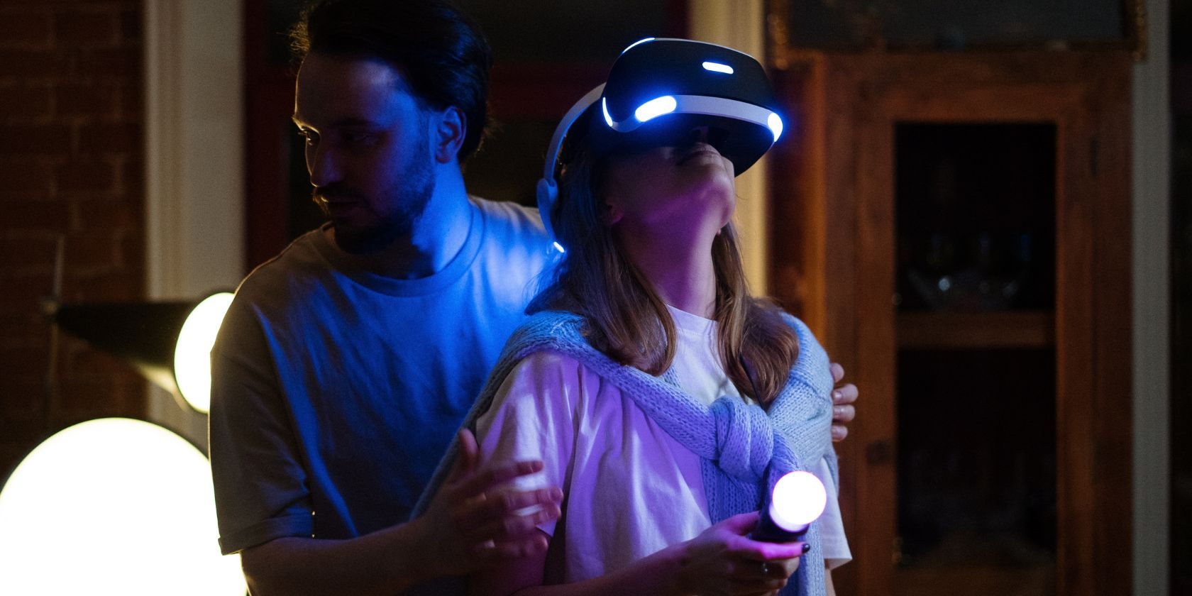 Man helping woman while she plays VR