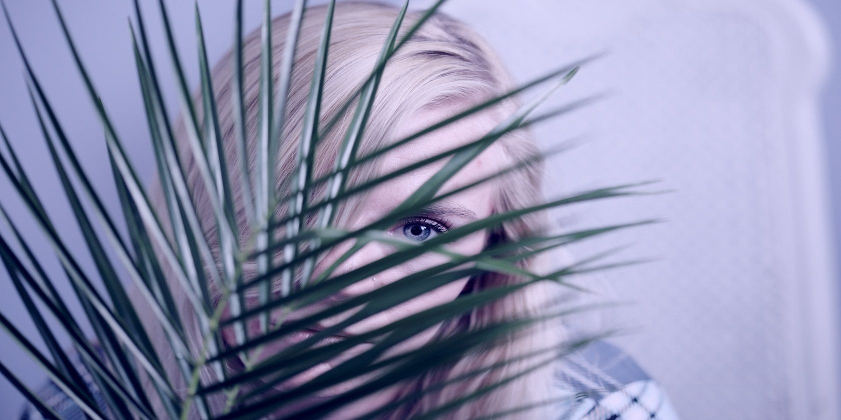 A woman peeping behind a palm leaf