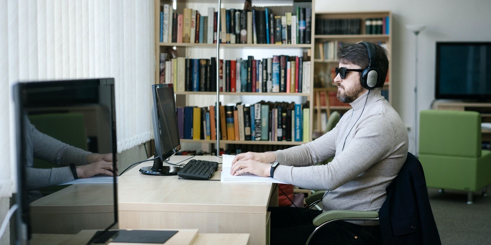 Visually Impaired Person using Braille in front of Computer