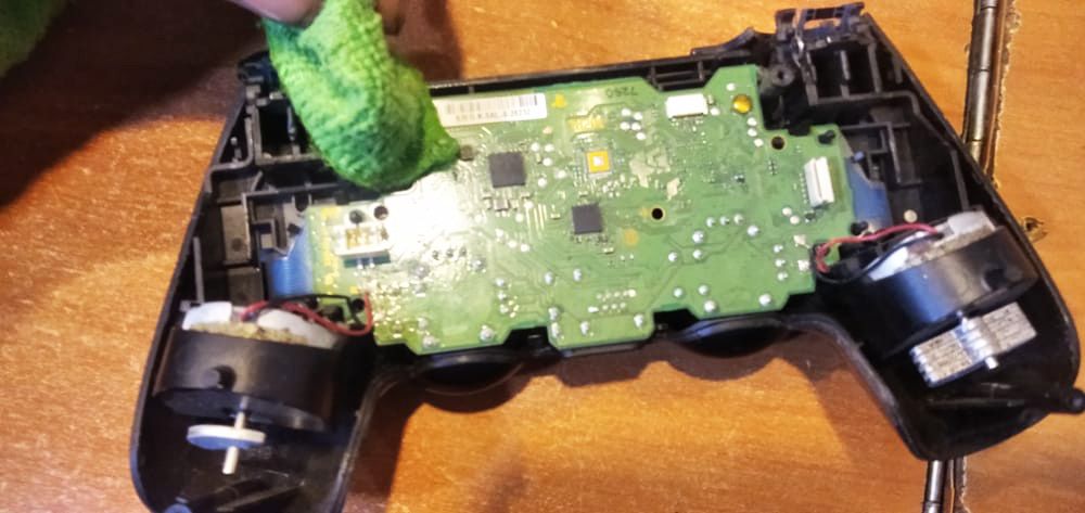 Using a piece of cloth dipped in alcohol to clean the motherboard of the ps4 controller