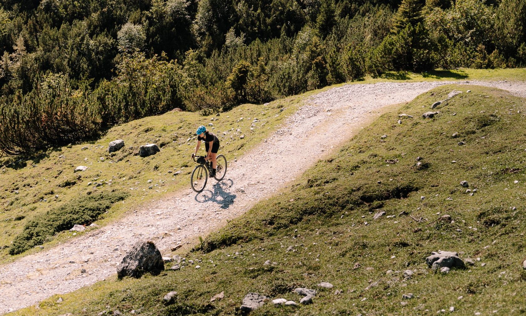 person cycling outdoors on a gravel path in the mountains