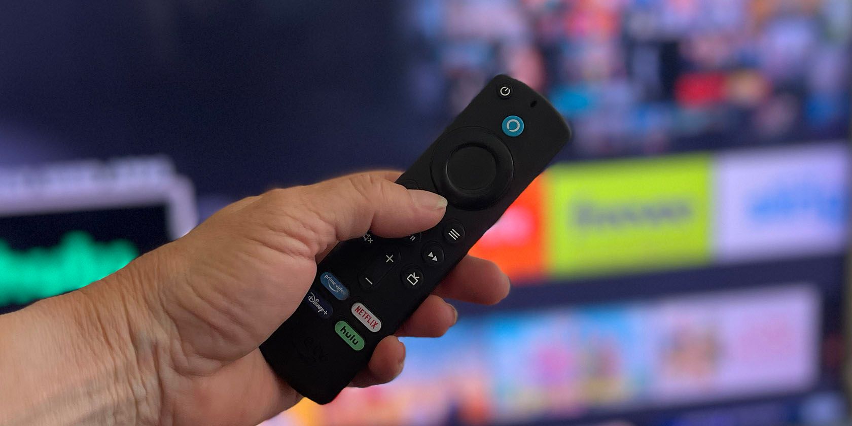 hand holding a Amazon Fire TV Voice Remote in front of TV 